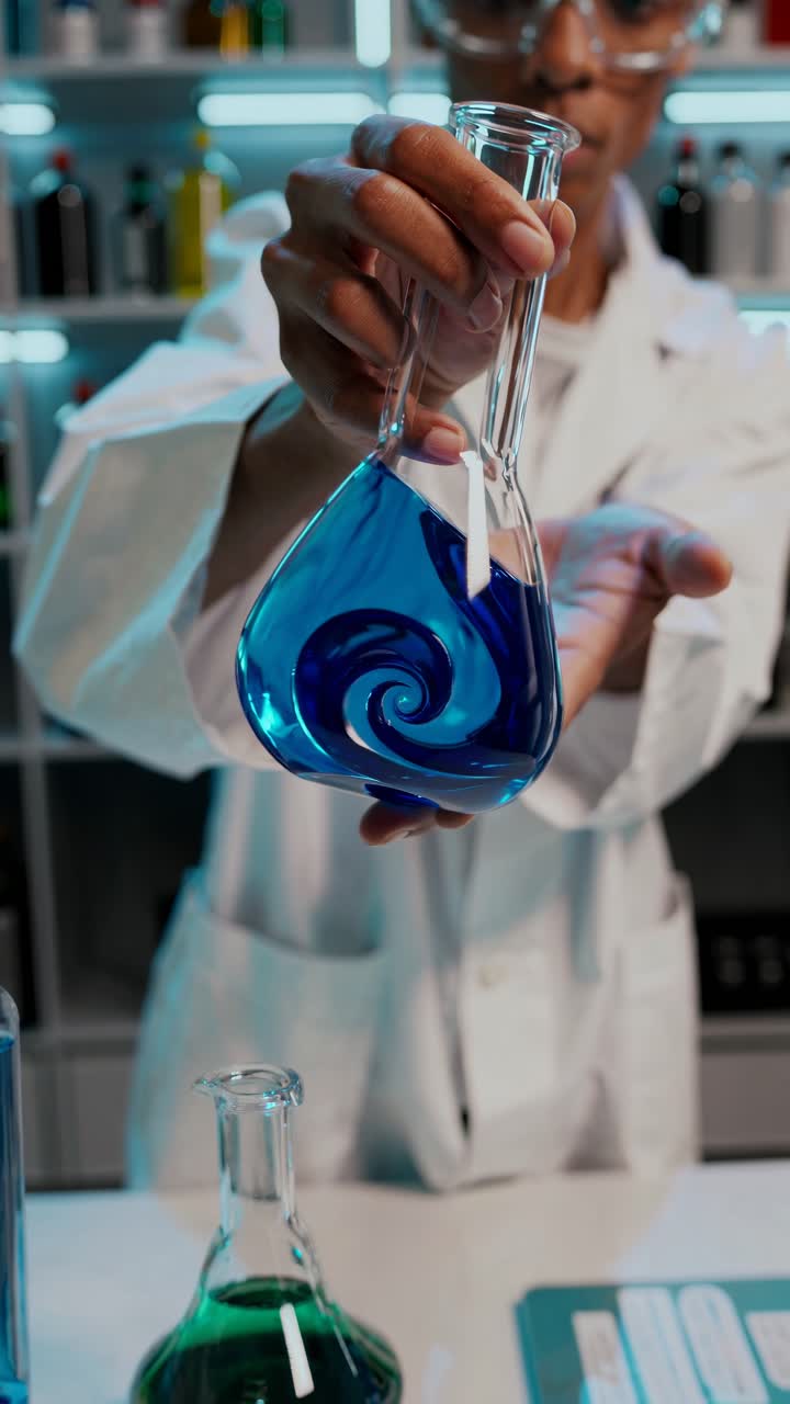 Scientist Swirling Blue Liquid in a Flask in a Laboratory