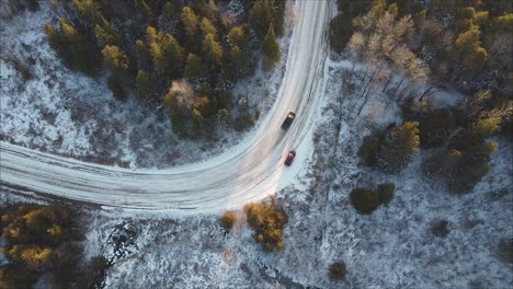 Top-Down-Aufnahme-Eines-Pickup-Trucks,-Der-Im-Winter-An-Einem-Geparkten-Auto-Auf-Der-Forststraße-Vorbeifährt