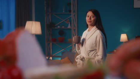 woman drinking a warm beverage in her home at night