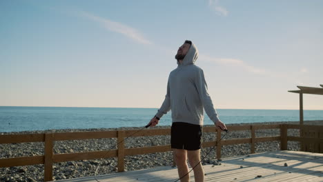 man skipping rope at beach pier
