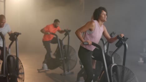 Diverse-group-fitness-class-training-hard-on-elliptical-bikes-at-gym,-in-slow-motion