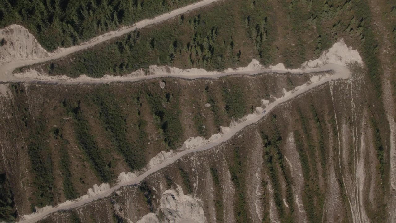 Filmato con drone della strada sterrata tortuosa a zigzag sul ripido versante montuoso al Passo Katu-Yaryk nella Repubblica dell'Altai, Russia, paesaggio di viaggio estivo.