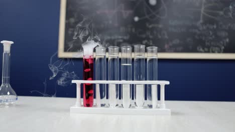 los tubos de ensayo se levantan mientras uno emite humo blanco del líquido rojo, una hipnotizante reacción química en progreso