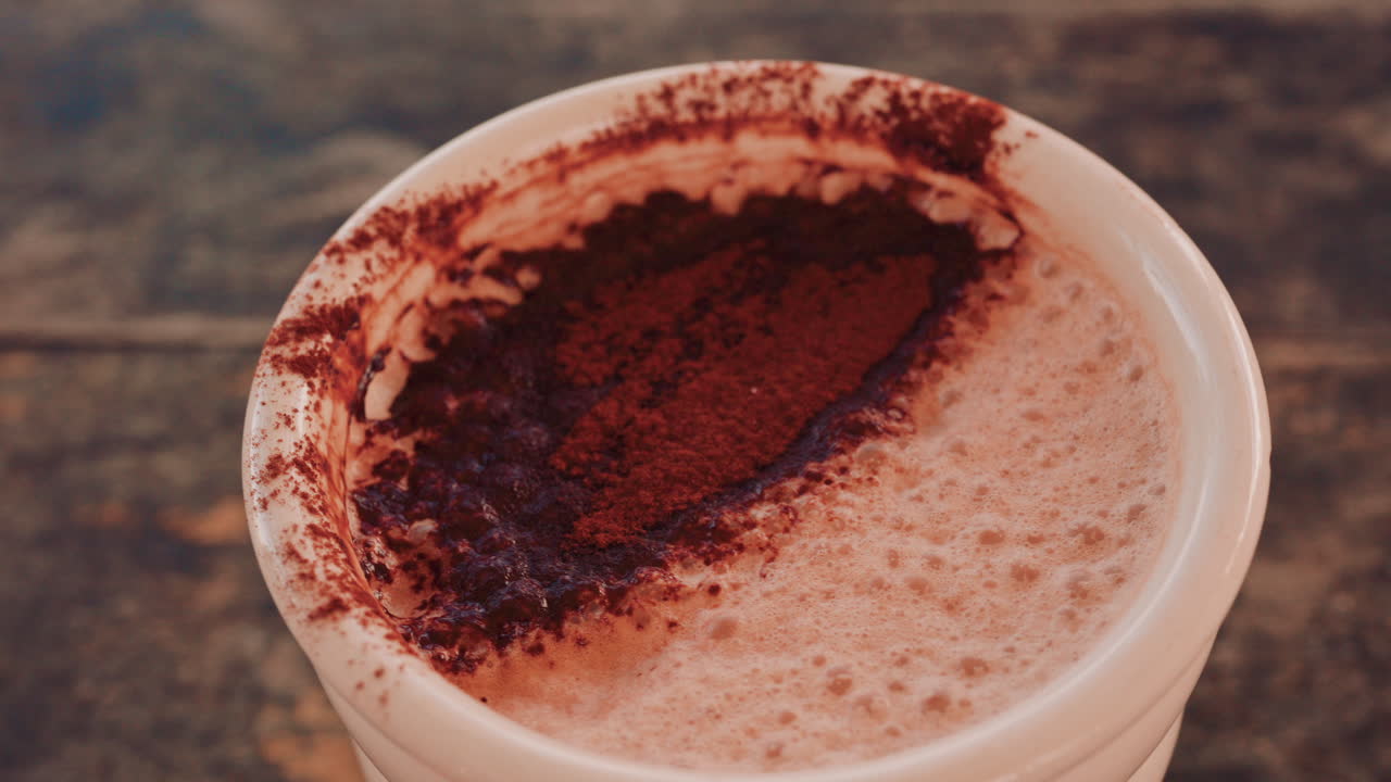 Primo piano di una ricca superficie di cioccolata calda o caffè cosparsa di cacao in polvere