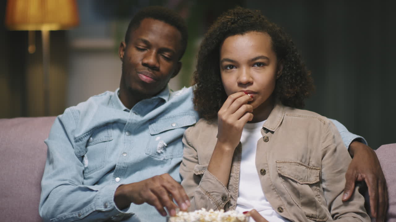 POV Of Afro Couple Eating Popcorn While Watching TV
