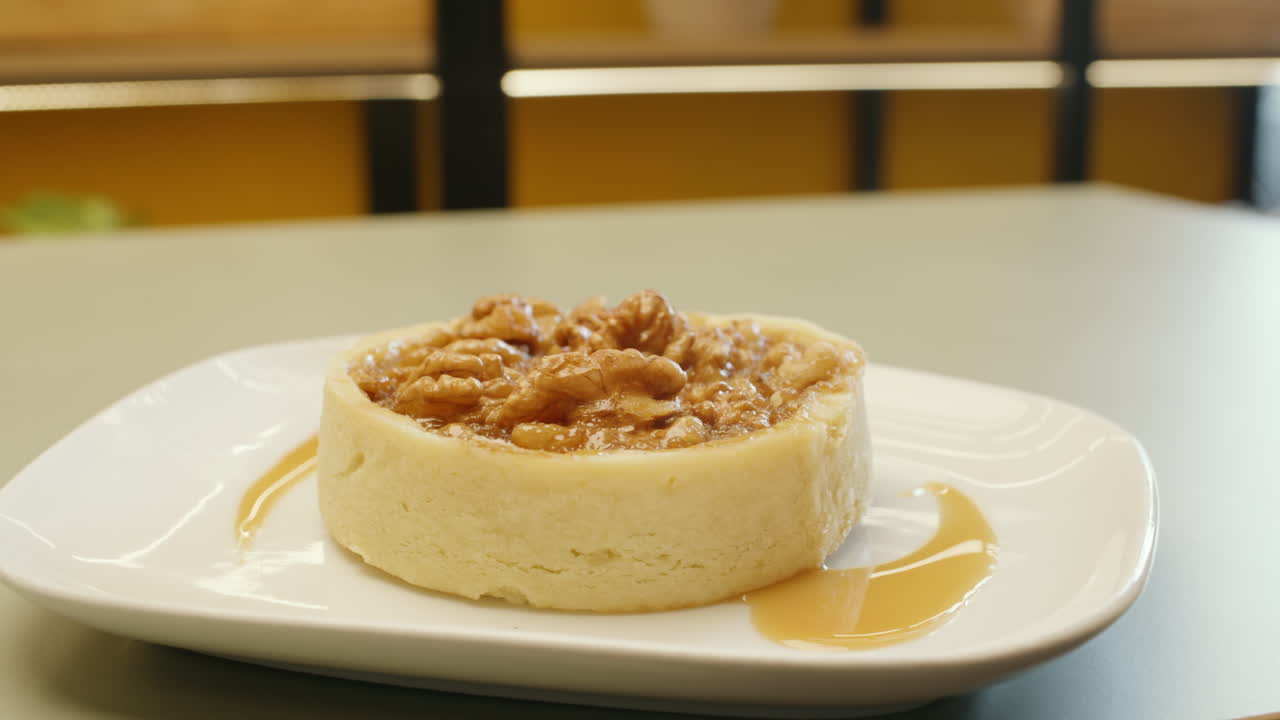 Panning shot of a cheesecake garnished with whole walnuts on top, highlighting its creamy texture and crunch