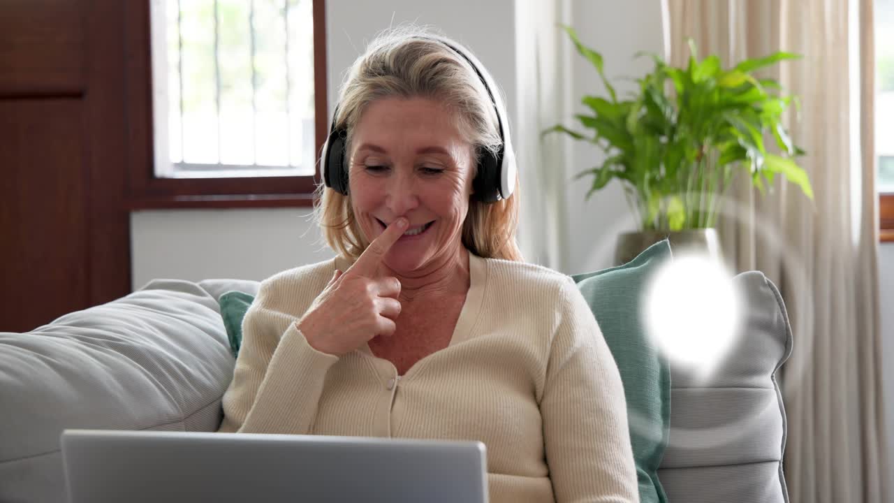 Mature woman reclining receiving call gesturing typing laptop joining remote call with UI icons