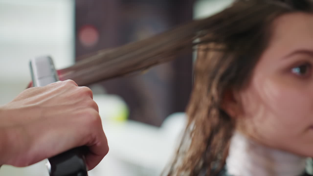 wet hair in salon, client receiving keratin-style straightening from stylist, close-up of plates gliding through sections and calm client face, professional salon lighting and cozy vibe