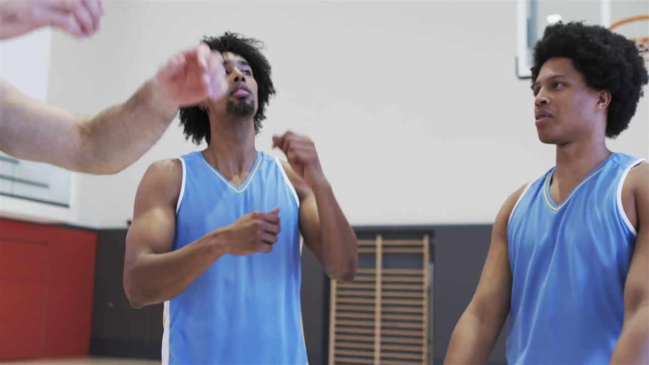 Happy diverse male basketball players stretching arms at training session, slow motion