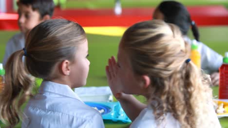 schoolgirls whispering while having meal