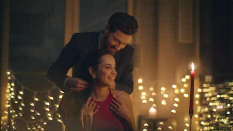 handsome man bringing necklace to woman at romantic dinner with candles closeup