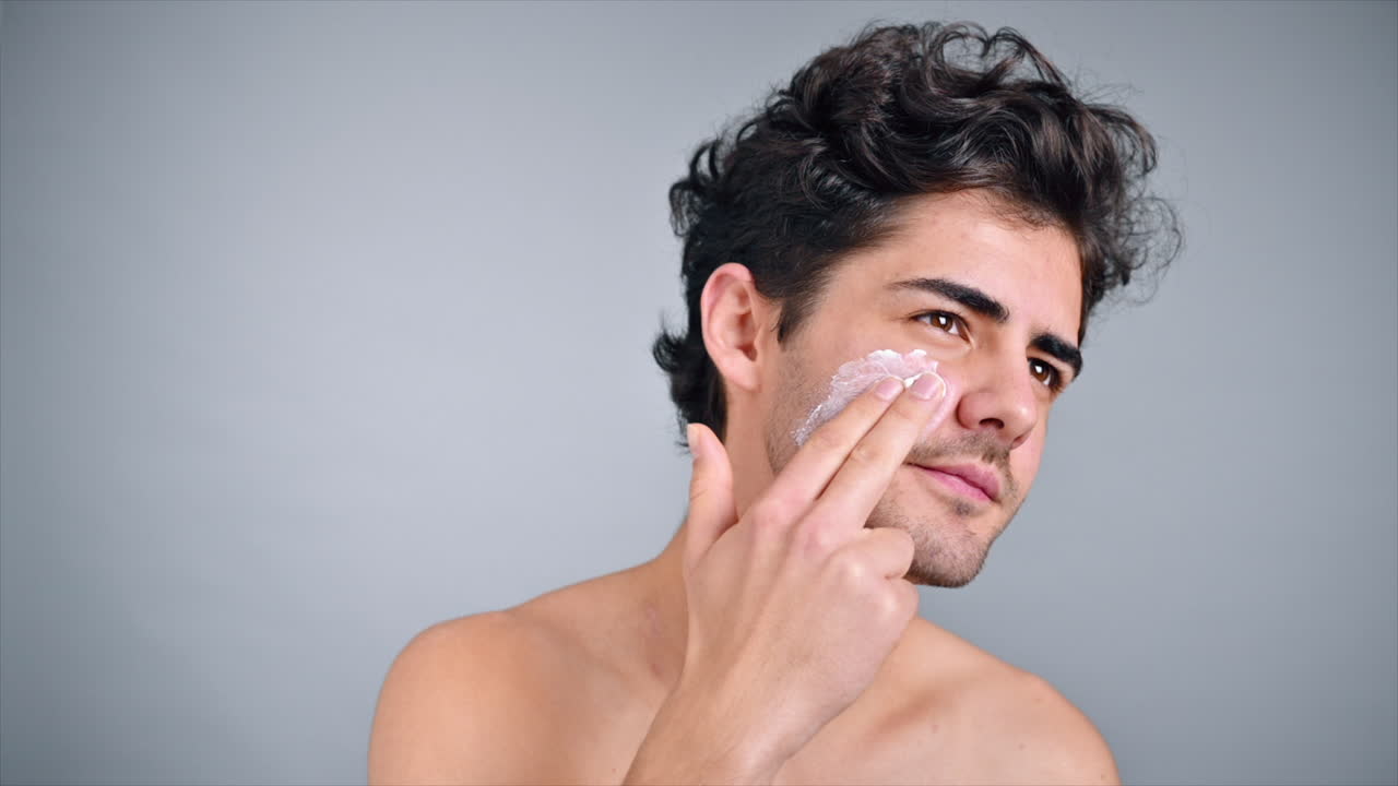 A young caucasian man with stubble beard is making a face mask. Slow motion