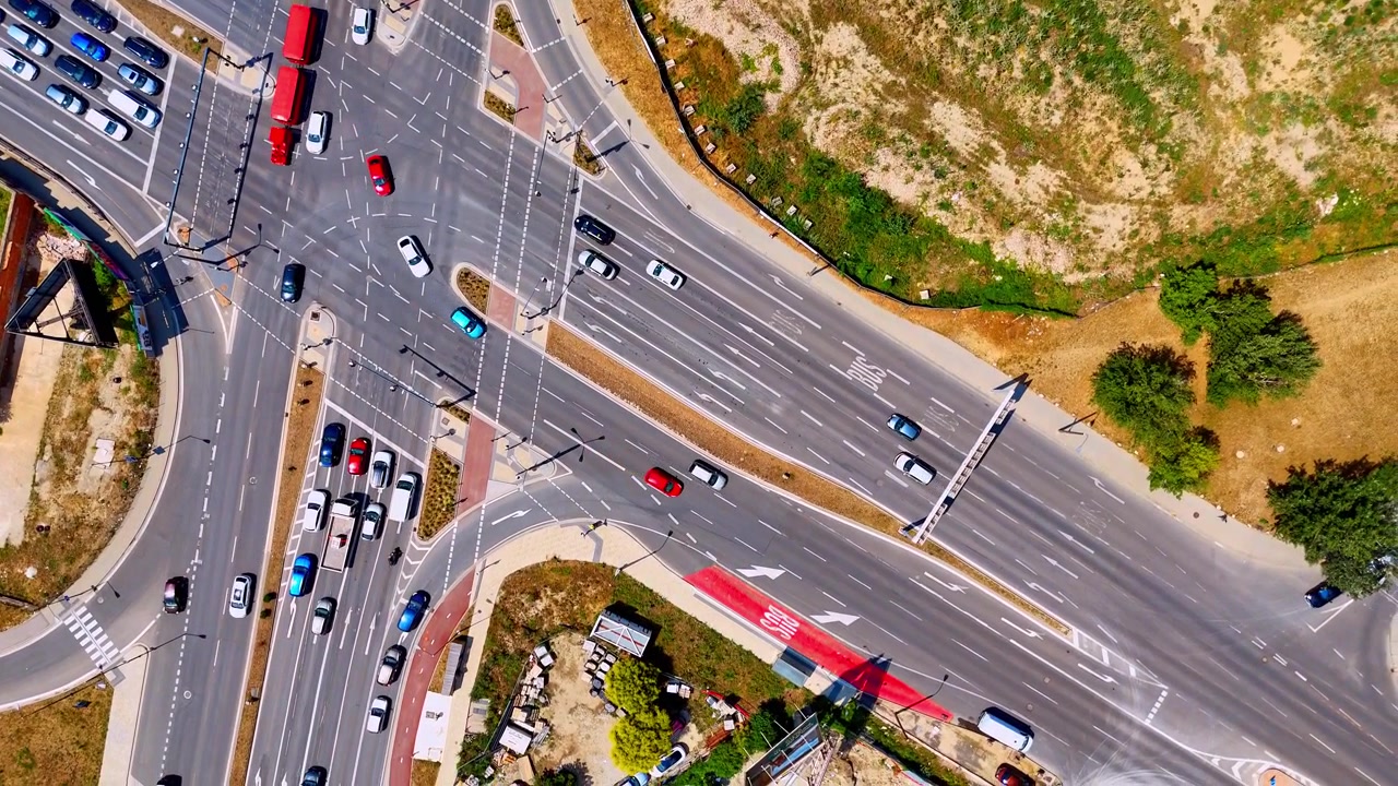 Wide drone view of traffic at a city crossroads, Bratislava, Slovakia. Top down frame displaying cars and buses moving along multi lane asphalt roads.