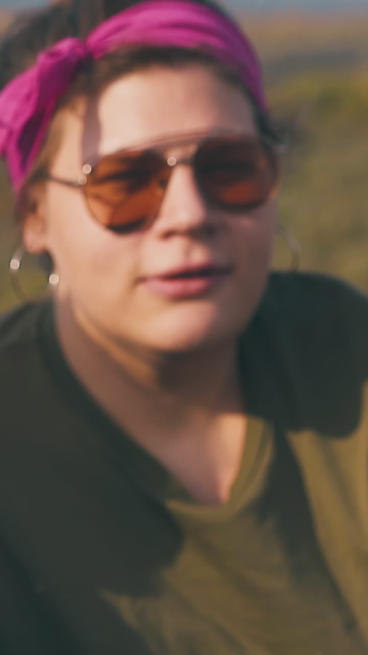 smiling tipsy young woman looks at lady hand strumming grass and throwing close view slow motion