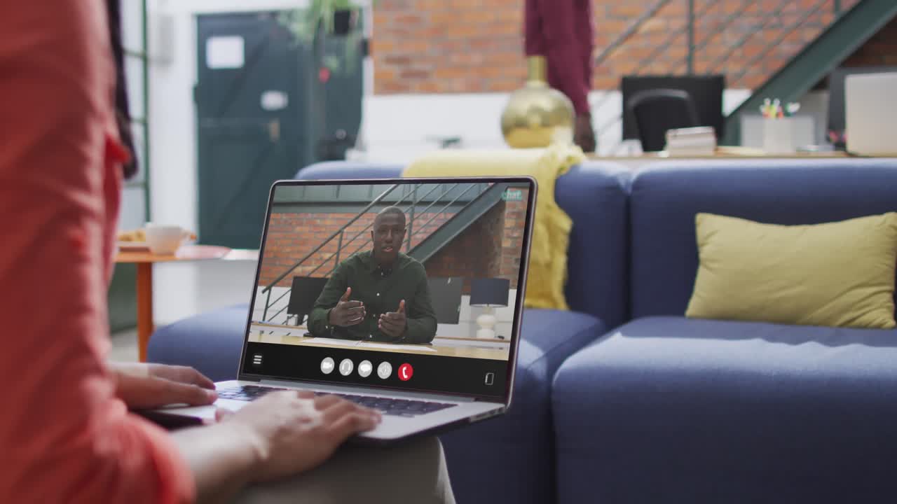 Biracial woman using laptop for video call, with business colleague on screen