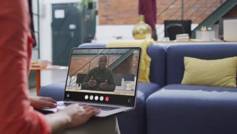 Mujer-Birracial-Usando-Una-Computadora-Portátil-Para-Videollamada,-Con-Un-Colega-De-Negocios-En-La-Pantalla