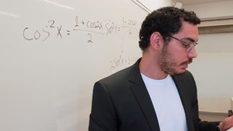 man writing a formula in a modern lecture hall