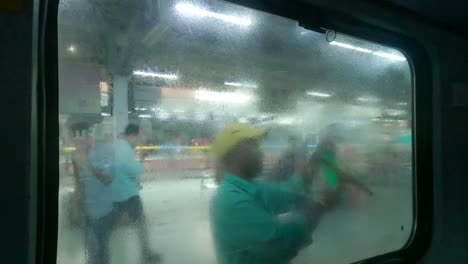 indian railway employee cleaning the windows of an ac coach