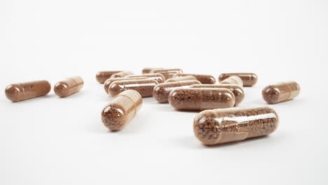 assortment of herbal brown capsules on white background with selective focus