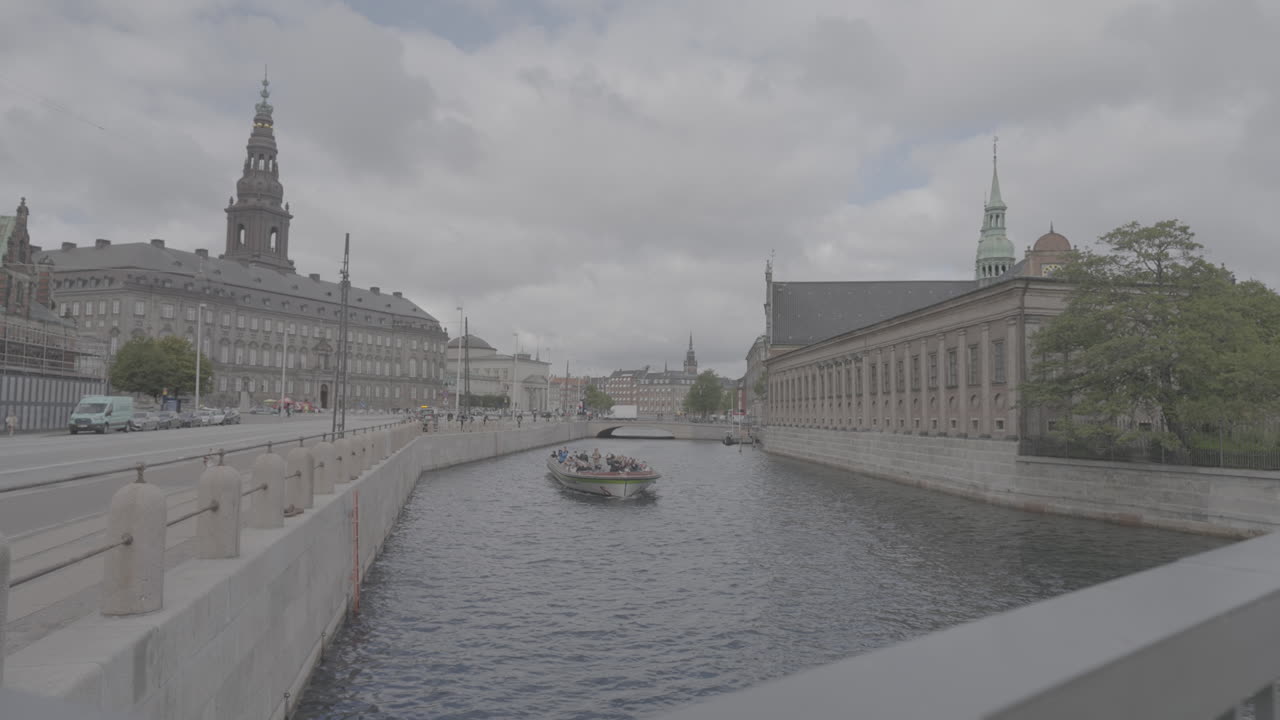 edificio christianborg en copenhague vista amplia sobre el río mientras un barco pasa en un registro de día nublado