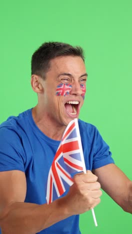 Man cheering for United Kingdom waving a national flag looking away
