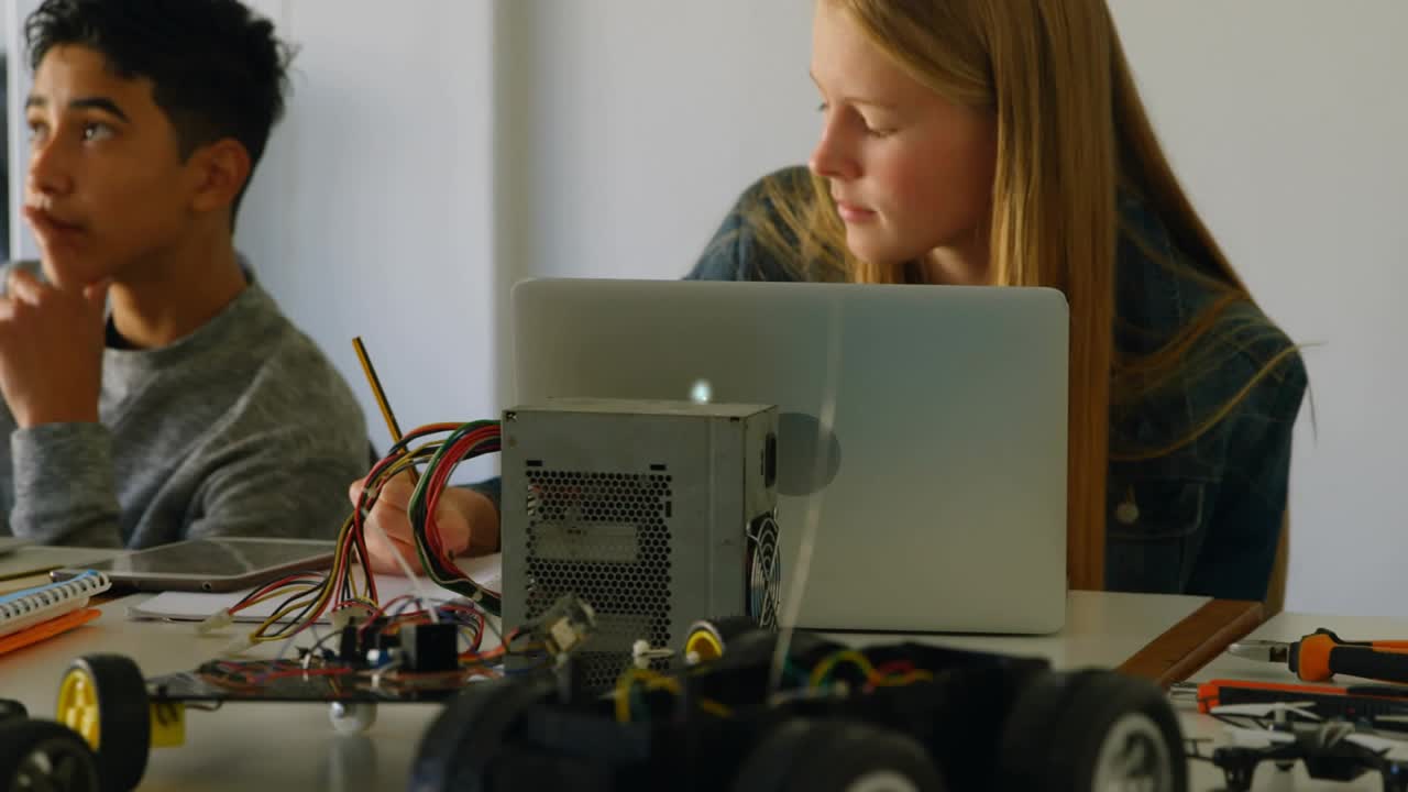Two students wiring and typing, laptop input causing animated nodes network covering STEM lab table
