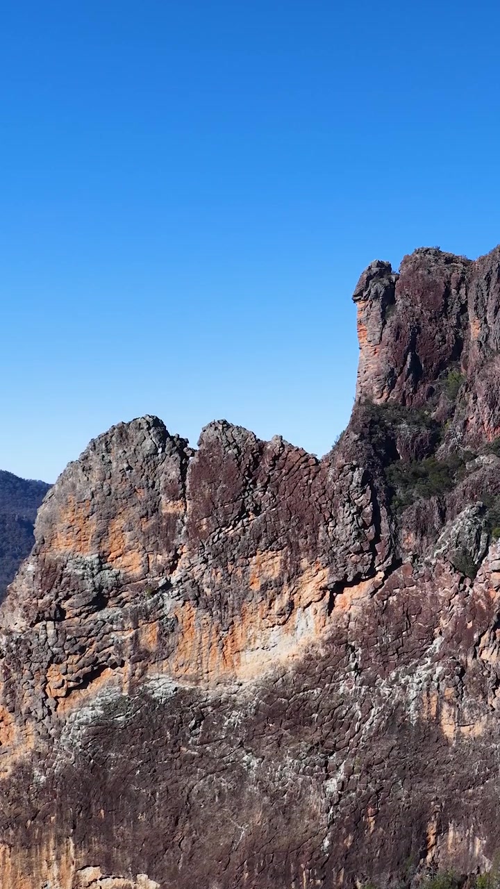 Cime montuose vulcaniche aspre sotto un cielo azzurro e limpido nel Parco Nazionale di Warrumbungle, Australia.