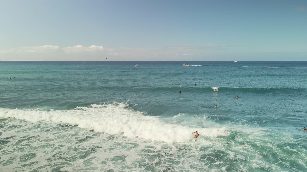 vista aérea de surfista montando olas en un soleado día hawaiano con cielo azul