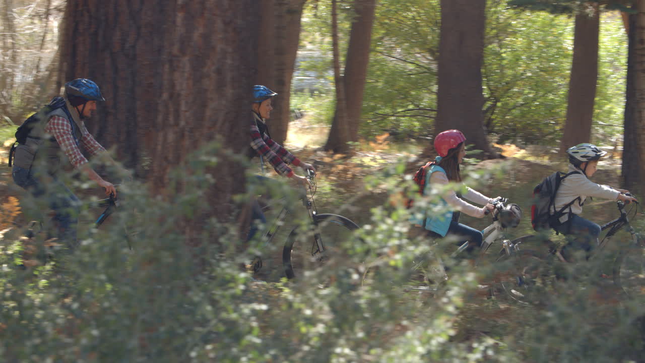 familia montando bicicletas de montaña a través de un bosque, disparo panorámico
