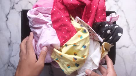 organizing baby clothes in a basket