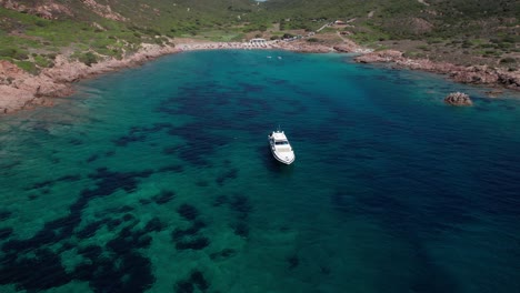 el círculo aéreo giró imágenes de un crucero en barco anclado en la isla de cerdeña, italia, cerca de la costa con personas disfrutando del verano en la playa.
