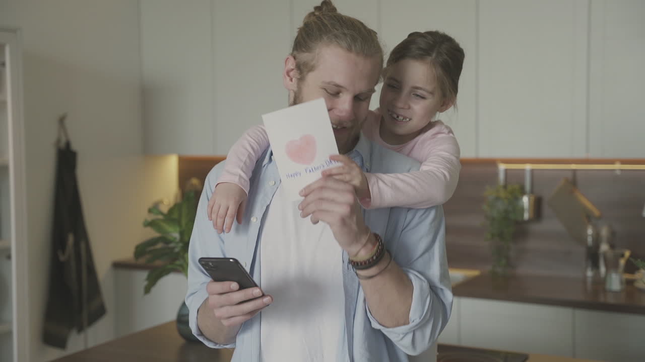 маленькая дочь обнимает и дарит поздравительную открытку