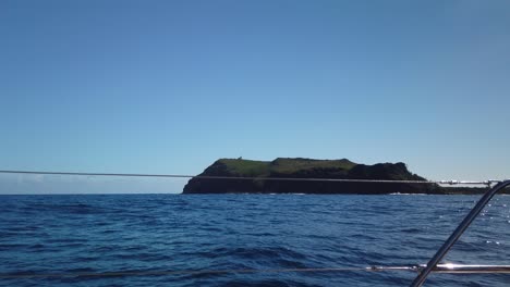 Una-Toma-Desde-El-Puerto-De-Un-Catamarán-De-Una-Isla-Con-Un-Faro-De-Mar-En-La-Parte-Superior