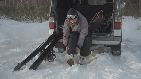 a splitboarder prepares gear in the snow by a van in iwanai, hokkaido, japan