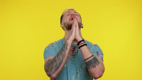 trendy stijlvolle man die bidt, omhoog kijkt en een wens doet, god om hulp vraagt, verontschuldiging smeekt