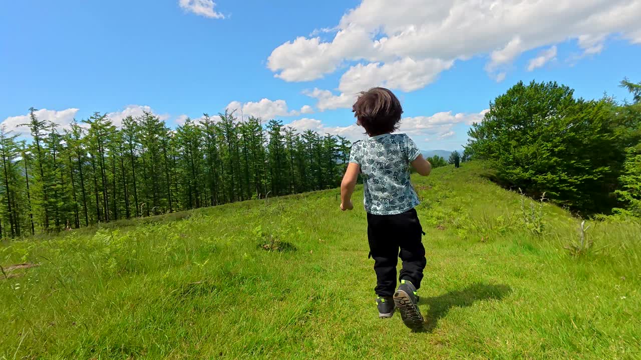 Boy running in a green field under a blue sky