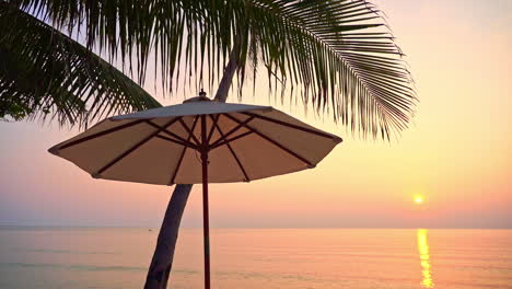 Una-Sombrilla-De-Playa-Solitaria-Se-Encuentra-En-Primer-Plano-Mientras-Las-Puestas-De-Sol-A-Lo-Largo-Del-Horizonte-Del-Océano