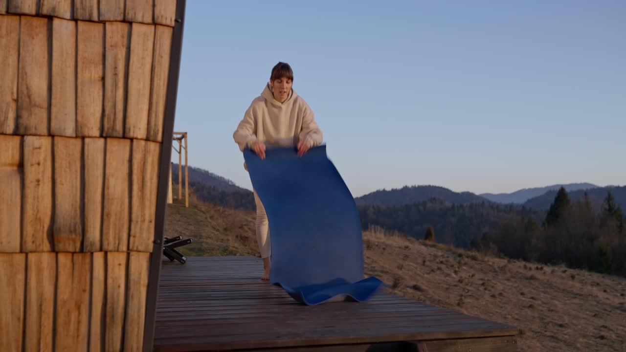 Woman doing yoga on a cabin deck in the mountains