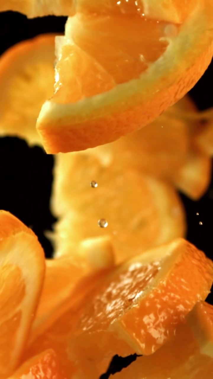 Fette d'arancia fresche che cadono con gocce d'acqua al rallentatore