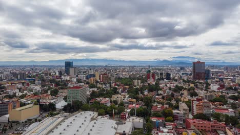 Hiperlapso:-Espectacular-Centro-De-La-Ciudad-De-México-Centro-Benito-Juarez-Barrio-Vuelo-Lateral-Sobre-Rascacielos,-Edificios,-Carreteras-Y-Carreteras-Con-Cordillera-En-El-Fondo-En-Día-Nublado,-Drone