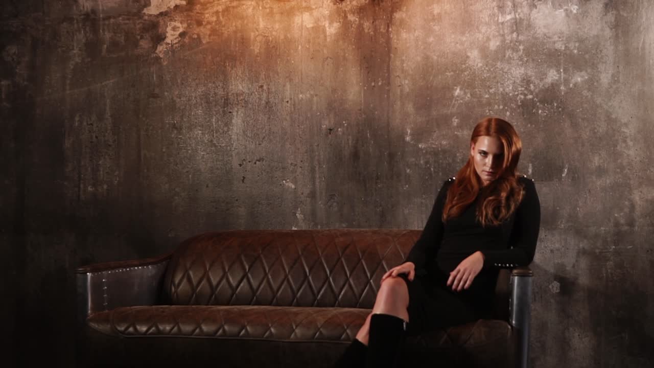 산업용 다락방 에 있는 가죽 소파 에 앉아 있는 여자