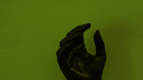 young female hand painted with black color moving smoothly in a green background