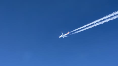 a massive white airbus 330 jet and its wake shot from the cabin of another jet flying bellow