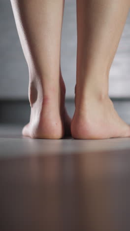 barefoot woman stands in bathroom doorway closeup. elegant lady prepares to take bath at home. flirty woman stands puts on tiptoe entering room