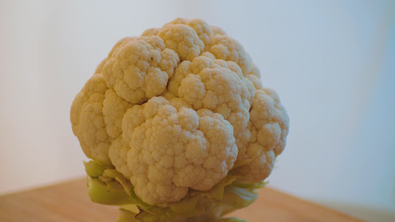 Cavolfiore bianco che gira su un piatto su un tavolo da cucina.