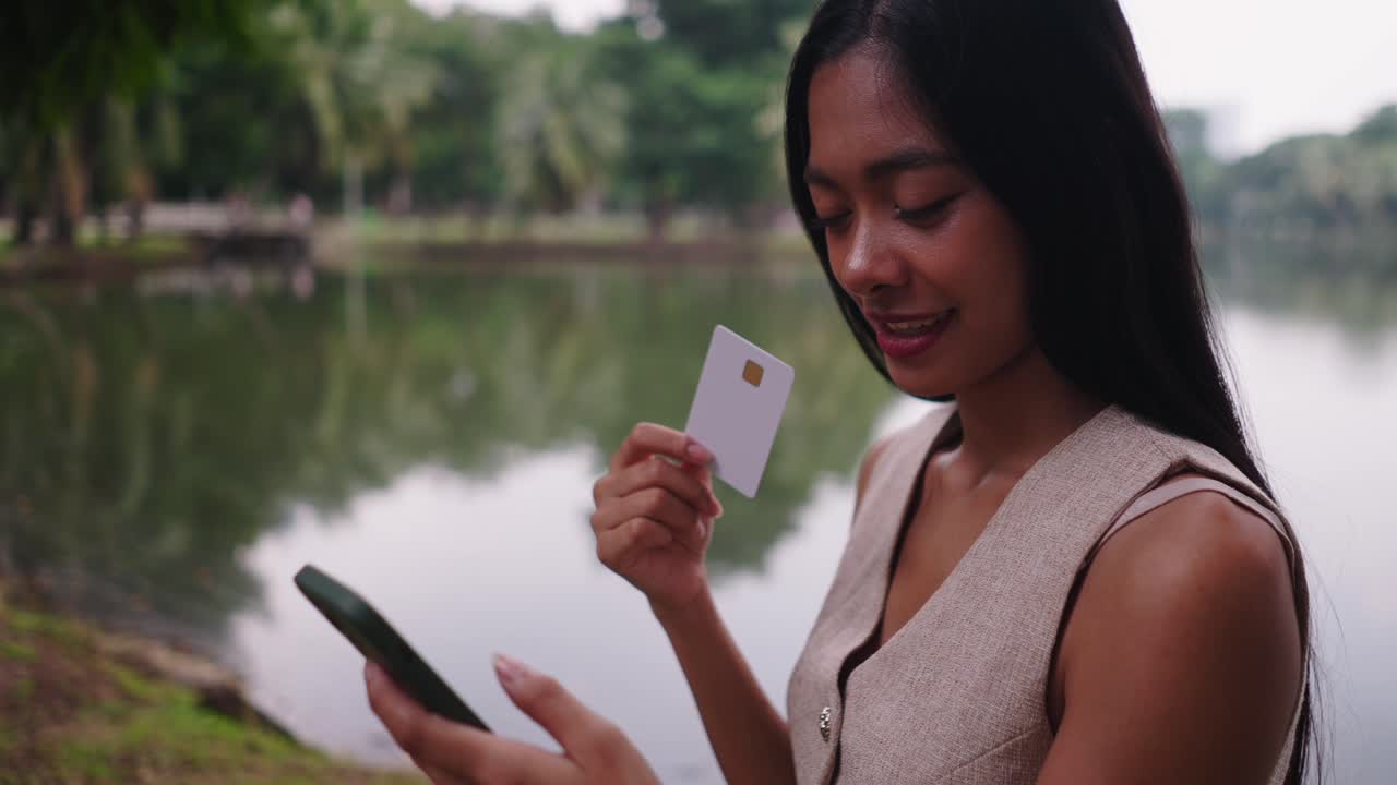 Mulher usando celular e cartão de crédito ao ar livre