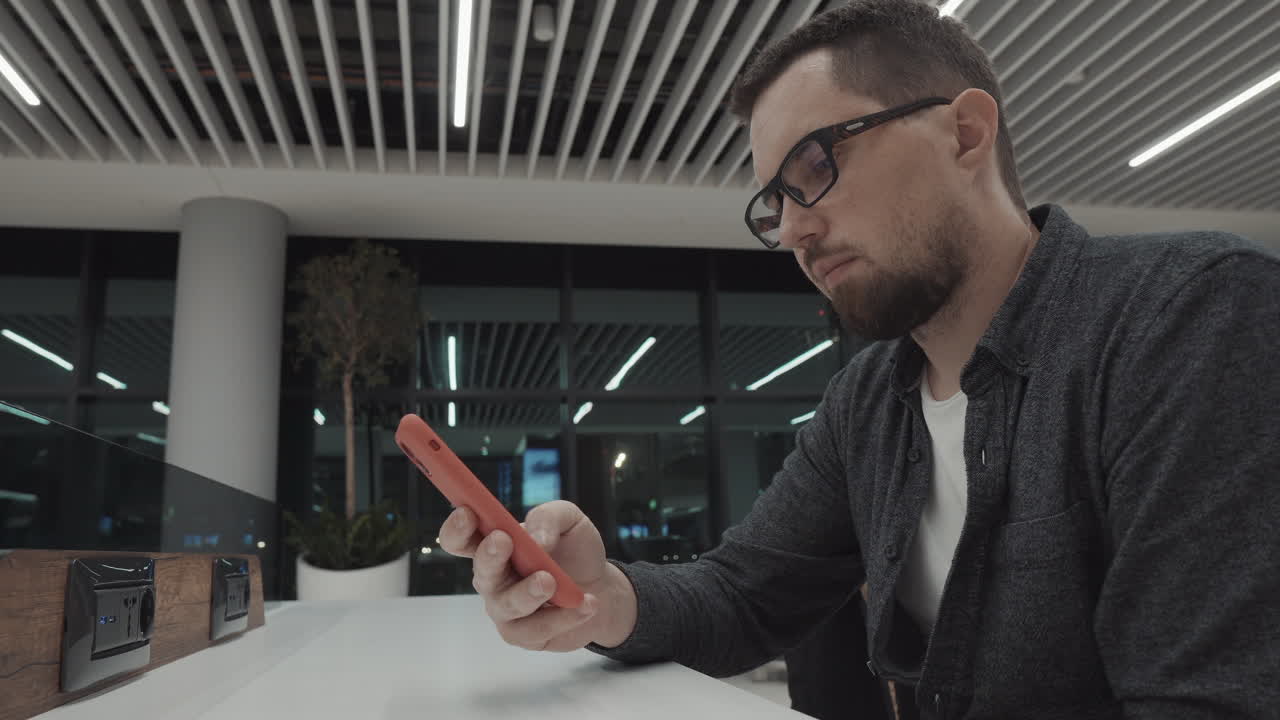 hombre usando teléfono inteligente en la sala de espera del aeropuerto por la noche