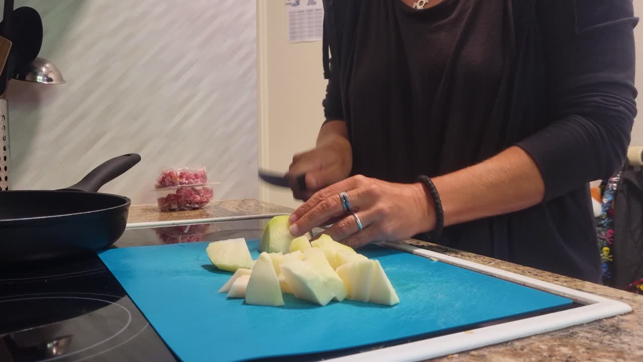 In her warm, inviting kitchen, a woman chops crisp kohlrabi, crafting a wholesome vegan meal with fresh, vibrant vegetables for home-cooked goodness, Switzerland, Europe