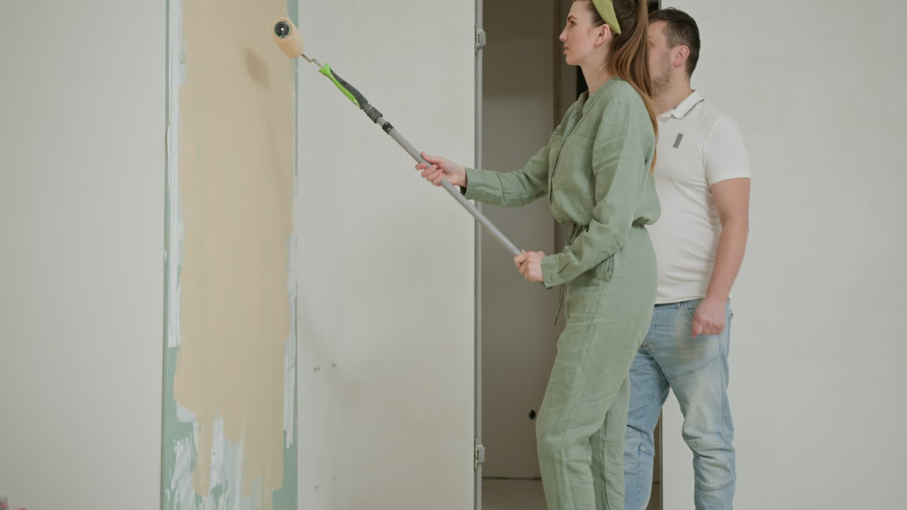 una pareja pintando una pared en su casa.