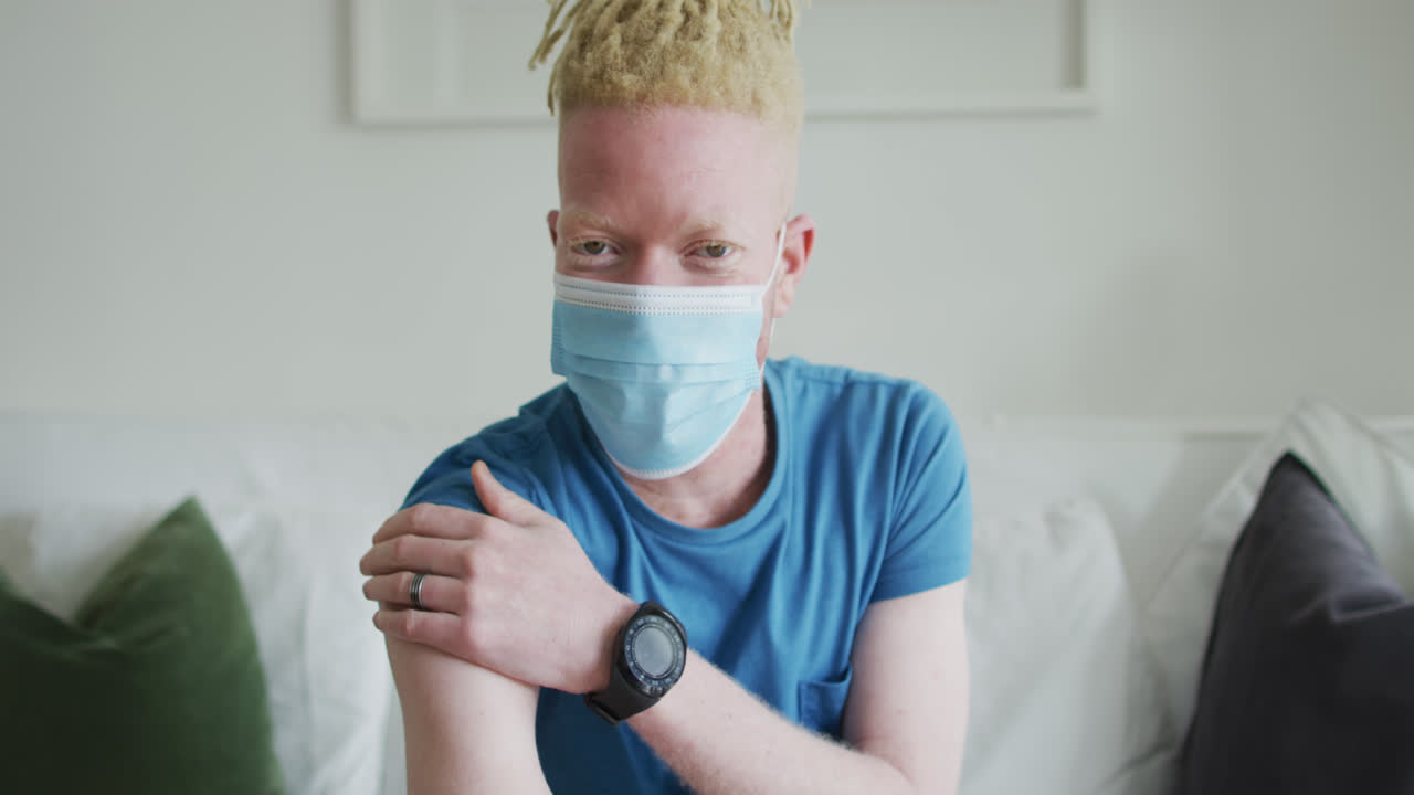 Happy albino african american man with dreadlocks and a plaster after vaccination